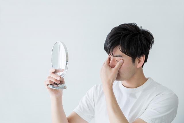 目もとの疲れを気にする男性