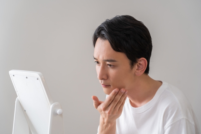 鏡でフェイスラインを確認する男性